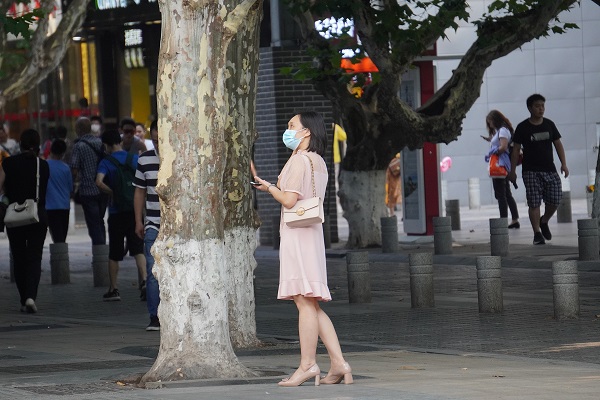 下班时间，一位女士站在树下等待约会对象。